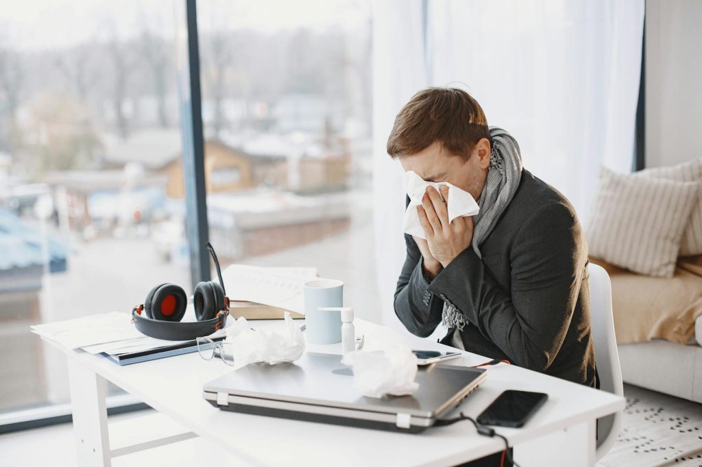 ill man sitting at desk and sneezing
